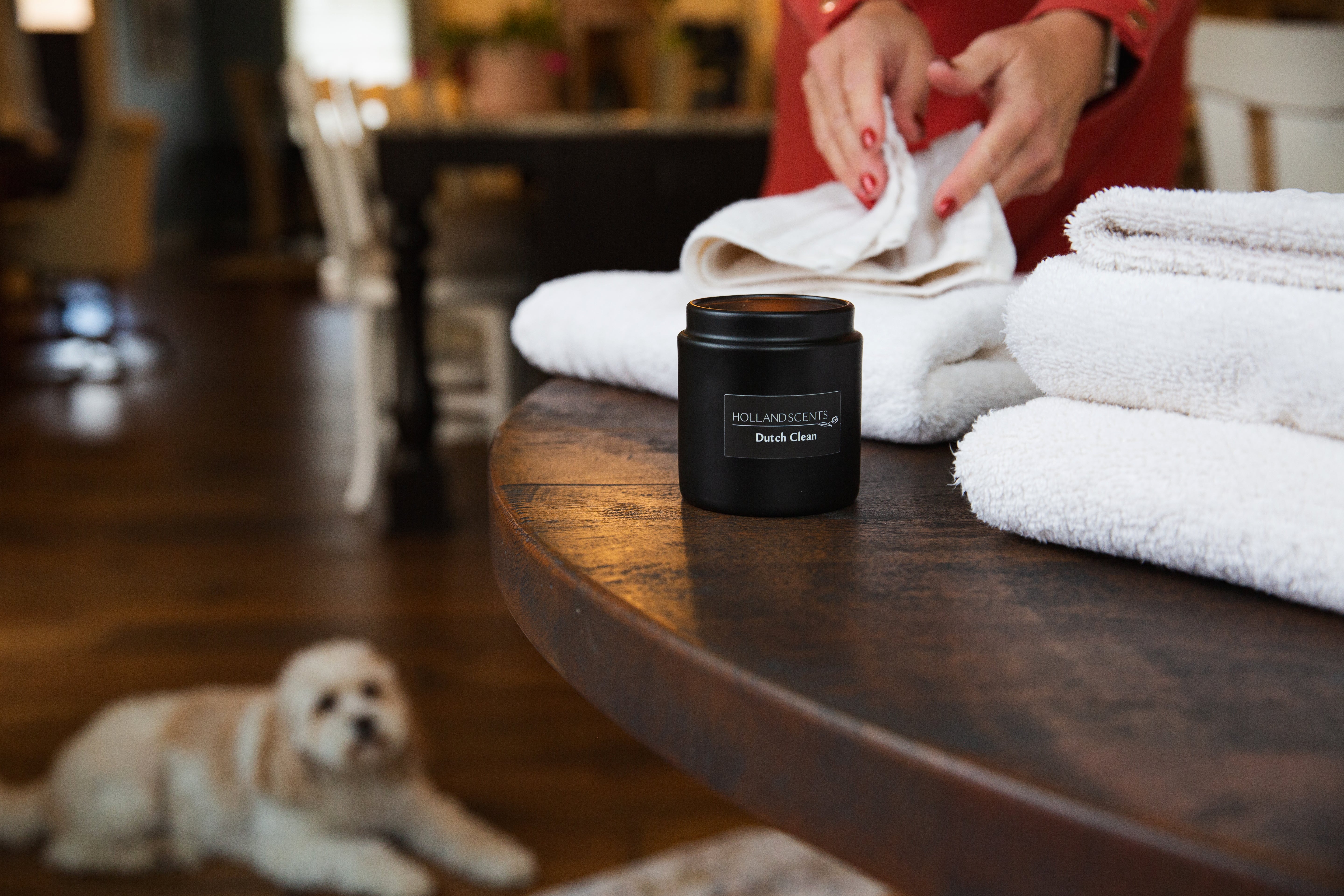 Holland Scents Dutch Clean soy candle on a table with folded towels and a dog in the background, Pella, Iowa
