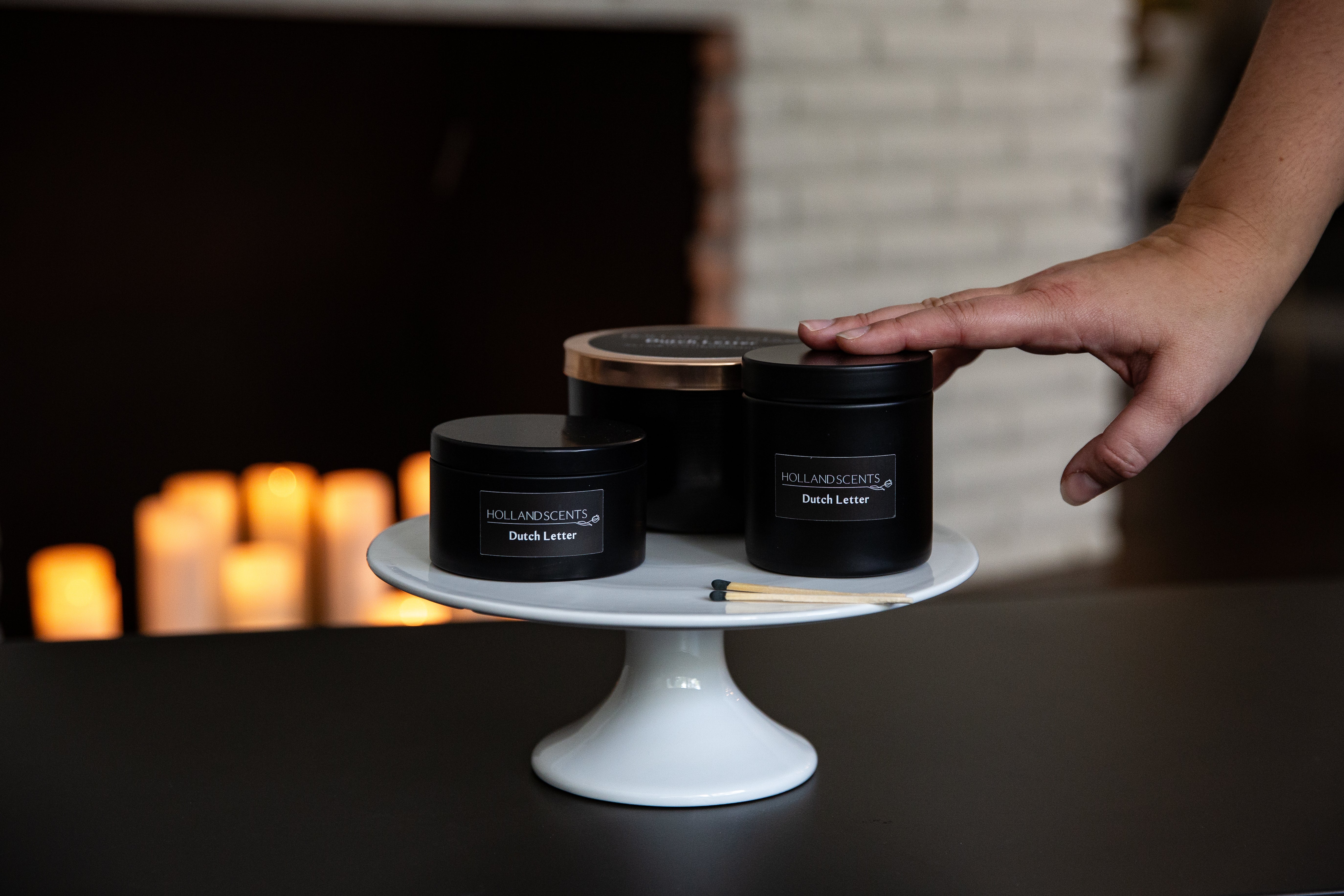 Holland Scents Dutch Letter soy candle in three sizes displayed on a cake stand, Pella, Iowa